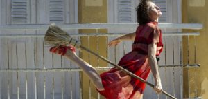a woman dance joyously in the sun with a broom