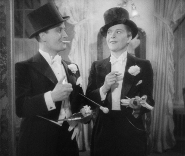 two people wearing vintage tuxedos and smiling at one another