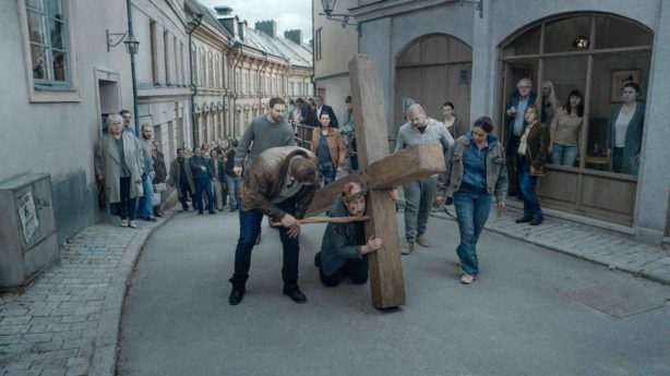 A man bloodied by his crown of thorns collapses under the weight of a cross as his taskmaster threatens and the town's people look on with curiosity at the passion play gone wrong in the Roy Andersson's ABOUT ENDLESSNESS.