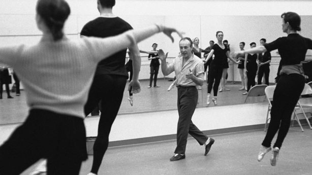 A black & white photo of George Balancine teaching his dance students.
