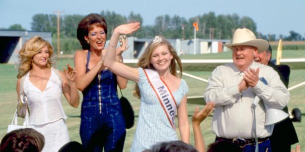 A girl onstage waving at a beauty pageant 