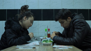 A young woman and man across a restaurant table from one another