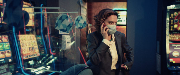 A masked woman on a cell phone looks to her left