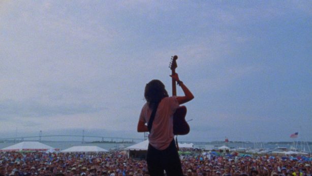 Courtney Barnett, her back turned to us, guitar in hand, facing an audience of thousands. 