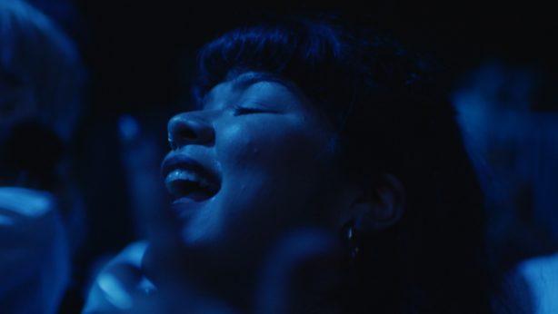 A woman singing under blue light.