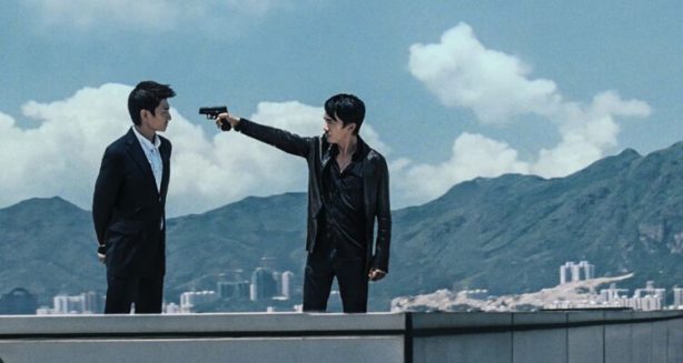 2 men on a building top, one with a gun to the head of the other, and Hong Kong in the backgroumd.