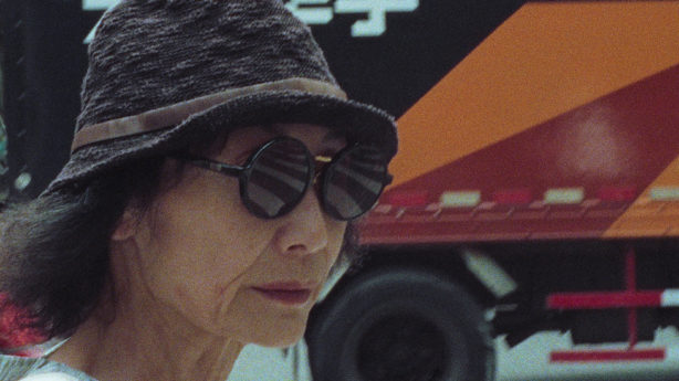 A partial profile of a mysterious woman in sunglasses and a hat.